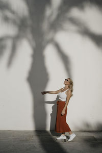 Portrait of young woman standing against wall