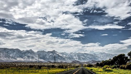 Road amidst field against sky