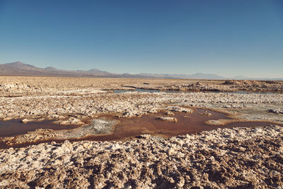 Scenic view of arid salt lake landscape against clear sky