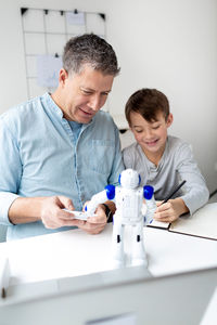 Father and son by toy and laptop on table at home