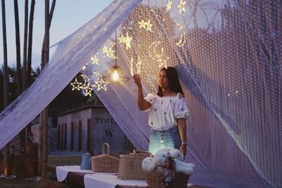 Woman holding an illuminated star while standing outdoors