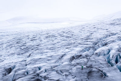 High angle view of hiker walking on snowcapped landscape