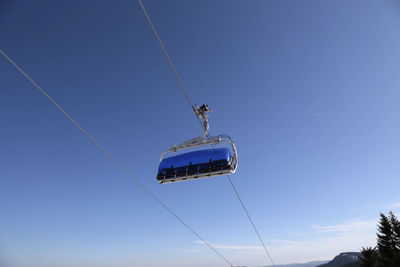 Low angle view of a ski lift against blue sky