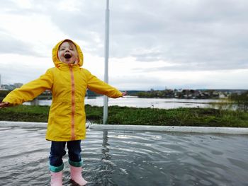 Full length of little girl standing against lake