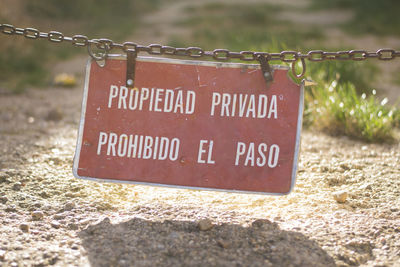 Close-up of information sign hanging on metal chain