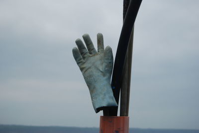 Close-up of hand by sea against sky