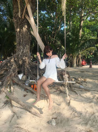 Full length of young woman sitting on swing