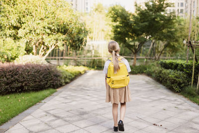 Back to school. little girl with yellow backpack from elementary school outdoor