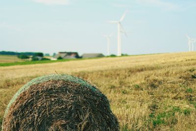 Wind turbines on field against sky