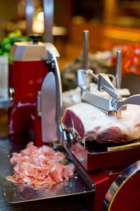 Close-up of meat and slicing machine on table