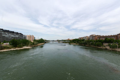 River amidst buildings in city against sky