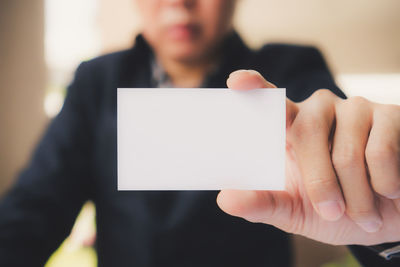 Midsection of businessman holding card