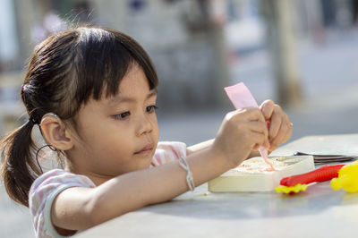 Close-up of cute girl playing with childs play clay at table outdoors