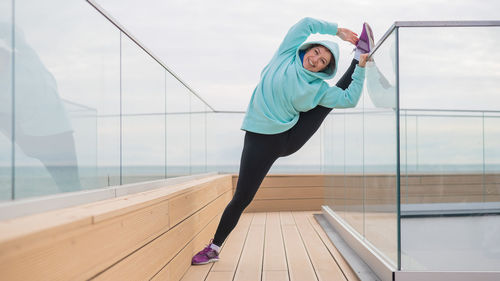 Full length of young woman exercising in gym