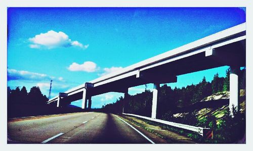 Road leading to bridge against blue sky