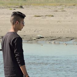 Side view of young man looking away at beach
