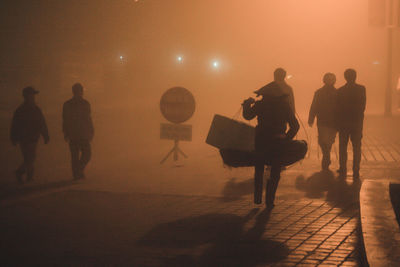 Silhouette people walking on road in city at night