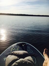 Low section of man by lake against sky