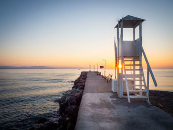 Lifeguard hut on beach against clear sky during sunset