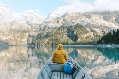 Rear view of person sitting on boat in lake