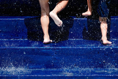 Low section of kids on blue steps amidst splashing water