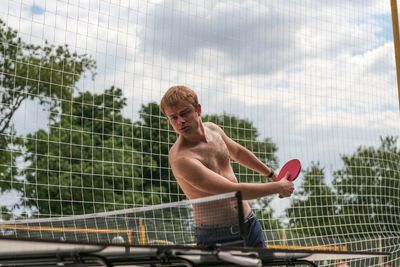 Shirtless young man playing table tennis