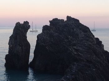 Scenic view of cliff by sea during sunset