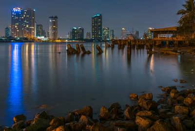 Illuminated buildings by chao phraya river against sky