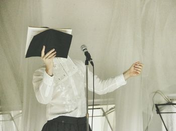 Man singing while standing against white curtains