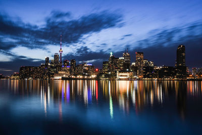 Illuminated modern buildings in city against sky at night