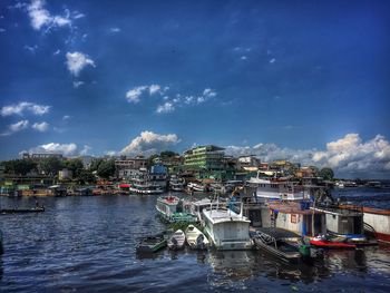 Boats moored in sea by town against sky