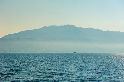 Scenic view of sea and mountains against clear sky