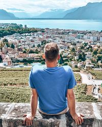 Rear view of man looking at cityscape against sea