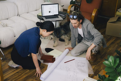 High angle view of multiracial male and female architects discussing over blueprint at home office