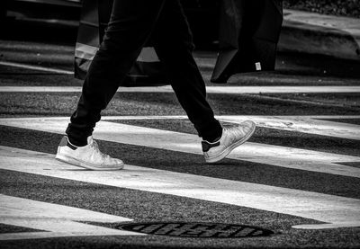 Low section of man walking on crosswalk