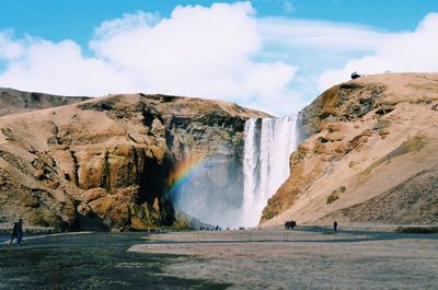 Scenic view of waterfall falling from mountain against sky