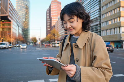 Young woman using mobile phone in city