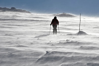 Person skiing on snow field against clear sky