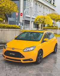 Yellow car on street against buildings