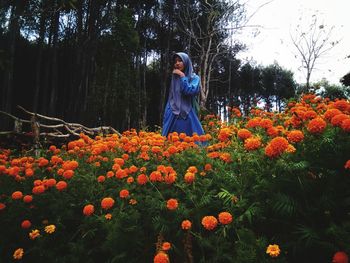 Full length of woman standing by flowering plants