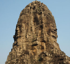 Low angle view of sculpture against sky at bayon temple during sunny day