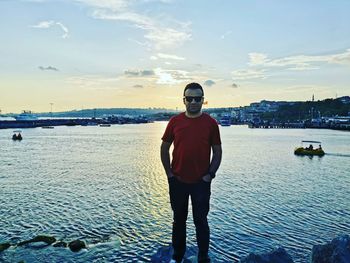 Man standing in sea against sky during sunset