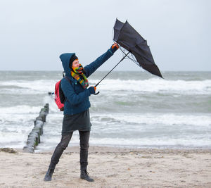 A woman tries to open an umbrella in stormy weather