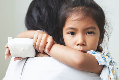 Mother carrying sick daughter against wall in hospital