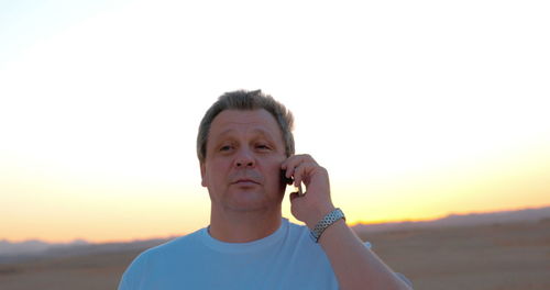 Portrait of young man against sky during sunset