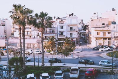 Cars on road by buildings in city against sky