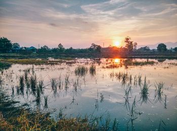 Scenic view of river against sky at sunset