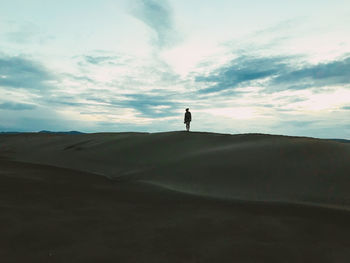 Silhouette man standing on field against sky