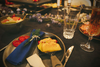 Close-up of raclette cheese served on a table with fresh vegetables, water and wine