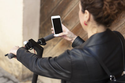 High angle view of woman using smart phone while riding push scooter